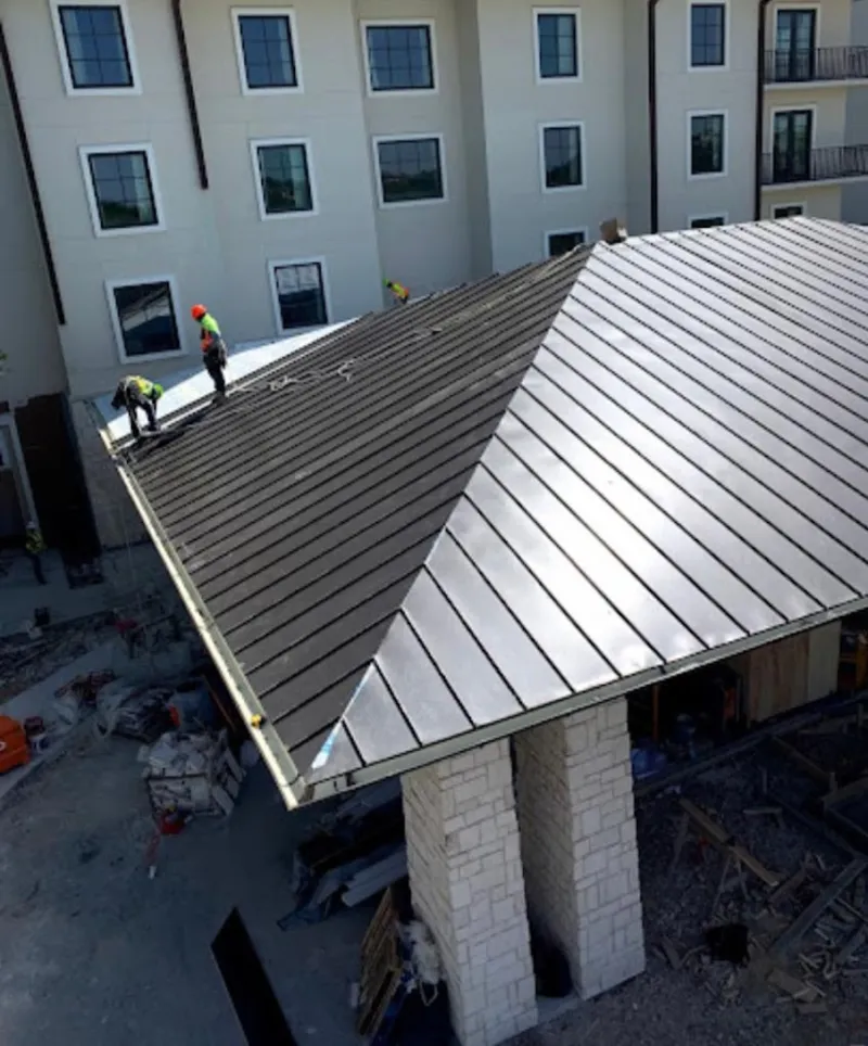 Crew installing standing seam metal roof panels on a commercial project in Radcliff
